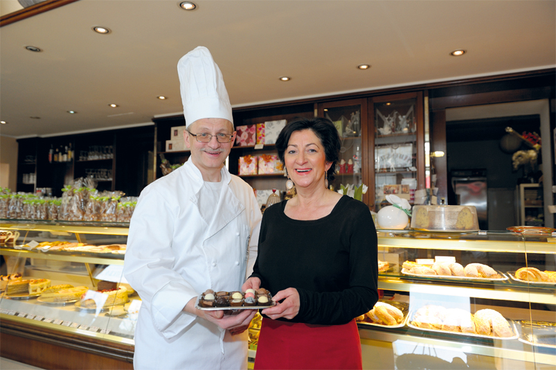 In einer Konditorei zeigen zwei Angestellte Pralinen