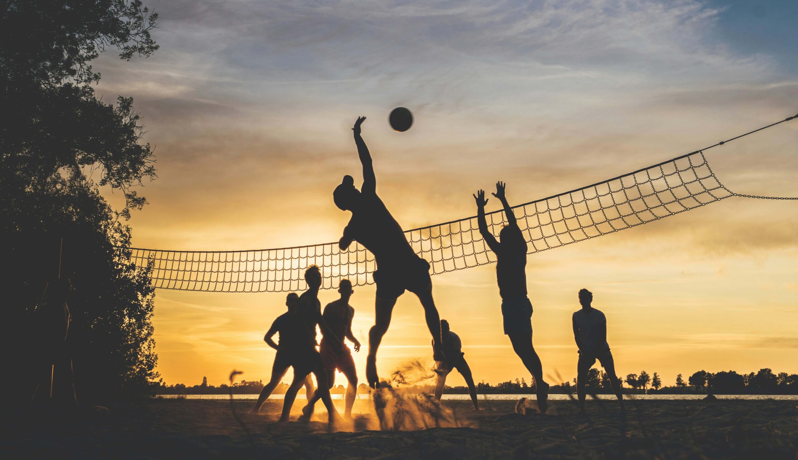 Menschen, die bei Sonnenuntergang Volleyball spielen