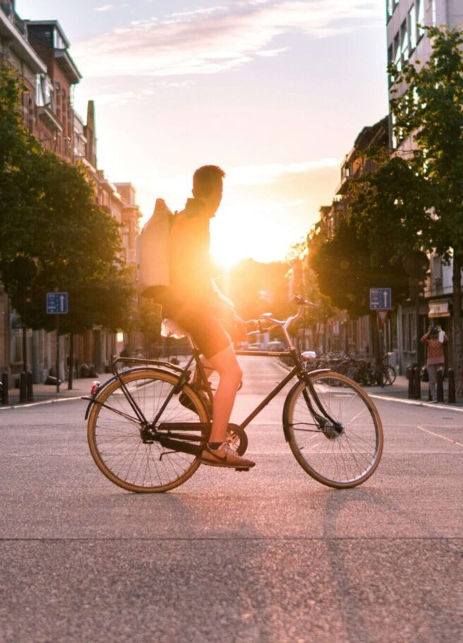 Fahrradfahrer in der Stadt sitzt auf seinem Fahrrad sieht in den Sonnenuntergang