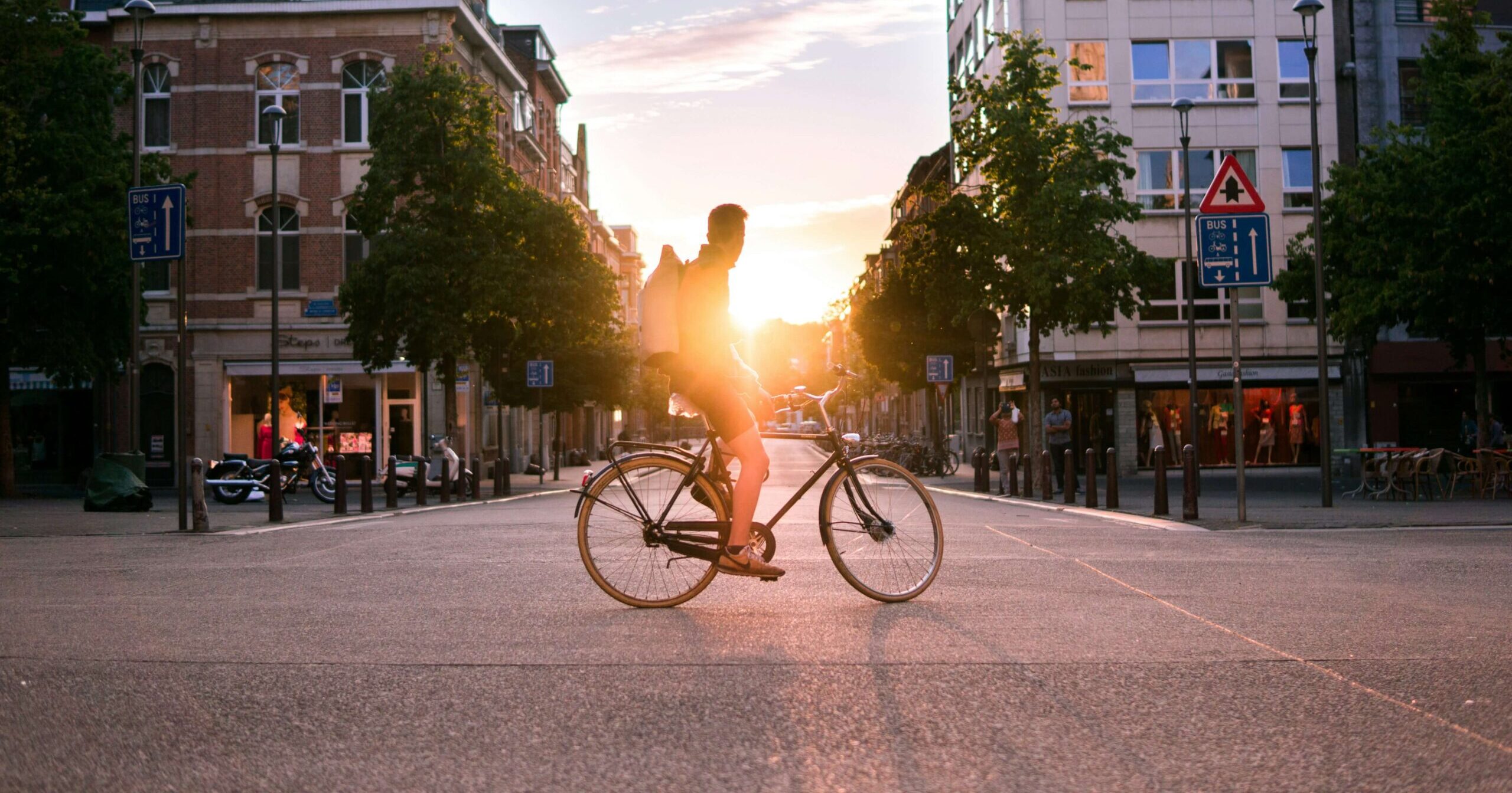 Fahrradfahrer in der Stadt sitzt auf seinem Fahrrad sieht in den Sonnenuntergang